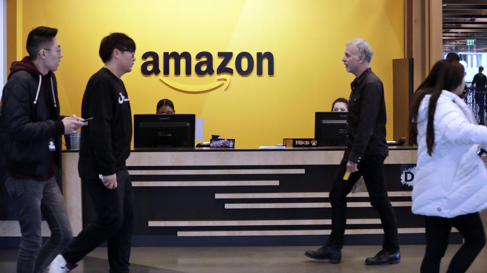 FILE - Employees walk through a lobby at Amazon's headquarters on Nov. 13, 2018, in Seattle. A group of Amazon workers upset about recent layoffs, a return-to-office mandate and the company's environmental impact is planning a walkout at its Seattle headquarters Wednesday. (AP Photo/Elaine Thompson, File)