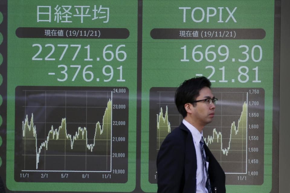 A man walks by an electronic stock board of a securities firm in Tokyo, Thursday, Nov. 21, 2019. Shares skidded Thursday in Asia after moderate declines on Wall Street as anxious mounted over the possibility the U.S. and China may not reach a trade deal before next year. (AP Photo/Koji Sasahara)