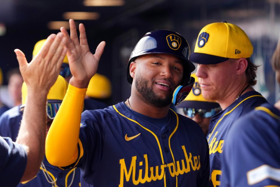 Milwaukee Brewers center fielder Jackson Chourio (11) high fives teammates after scoring a run against the San Diego Padres during the first inning of a Spring Training game at Peoria Sports Complex.
