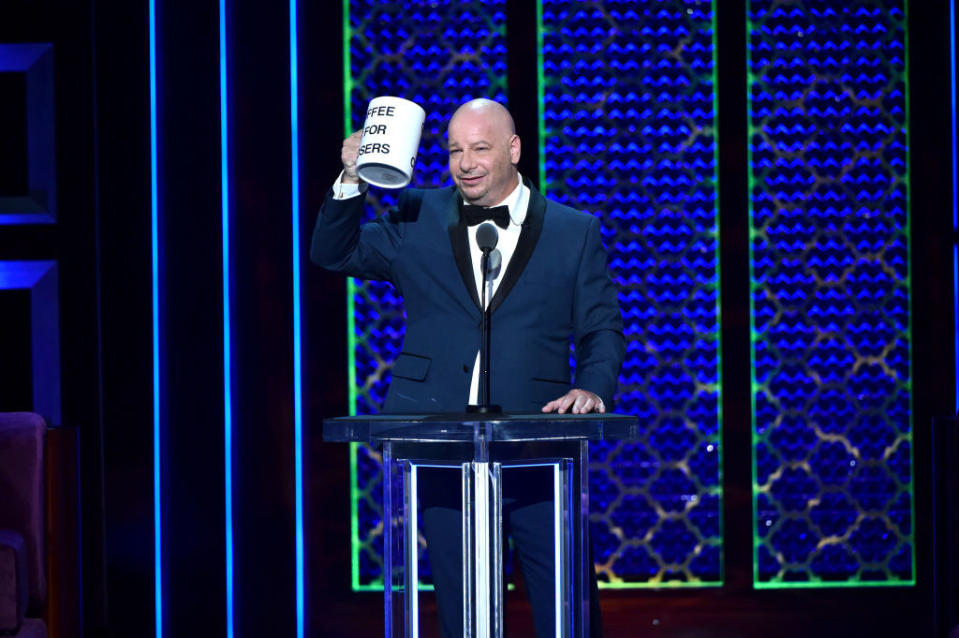 Jeff standing at a podium with comically large mug in hand