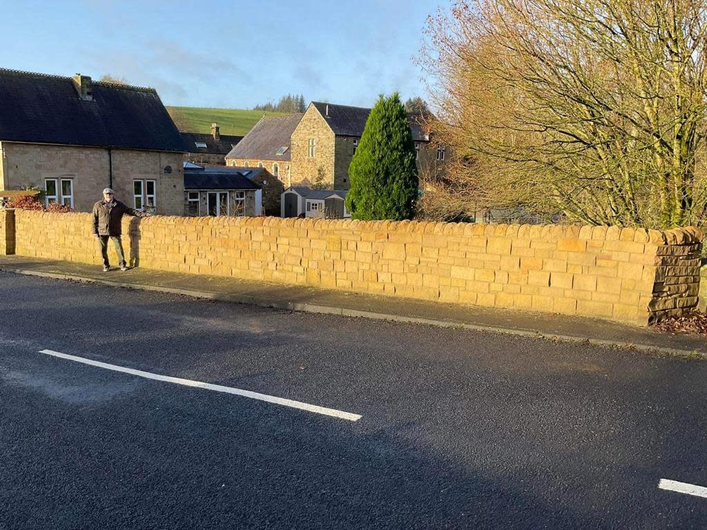 Bear Mason, 74, beside the 4ft stone wall which Northumberland County Council are threatening to demolish unless it is lowered by 8 inches. (SWNS)