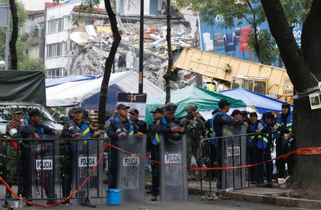 Soldiers and police officers stand guard next to a collapsed building after an earthquake in Mexico City, Mexico September 21, 2017. REUTERS/Henry Romero