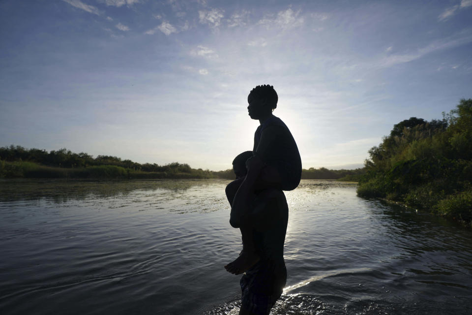 A father carries his daughter over the Rio Grande river toward Del Rio, Texas, from Ciudad Acuna, Mexico, early Wednesday, Sept. 22, 2021, as migrants, many from Haiti, go back and forth across the border. (AP Photo/Fernando Llano)