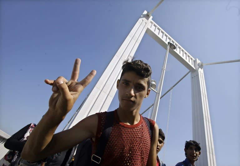 A migrant flashes a V-sign as hundreds of migrants walk across Budapest after leaving the transit zone of the main train station, on September 4, 2015