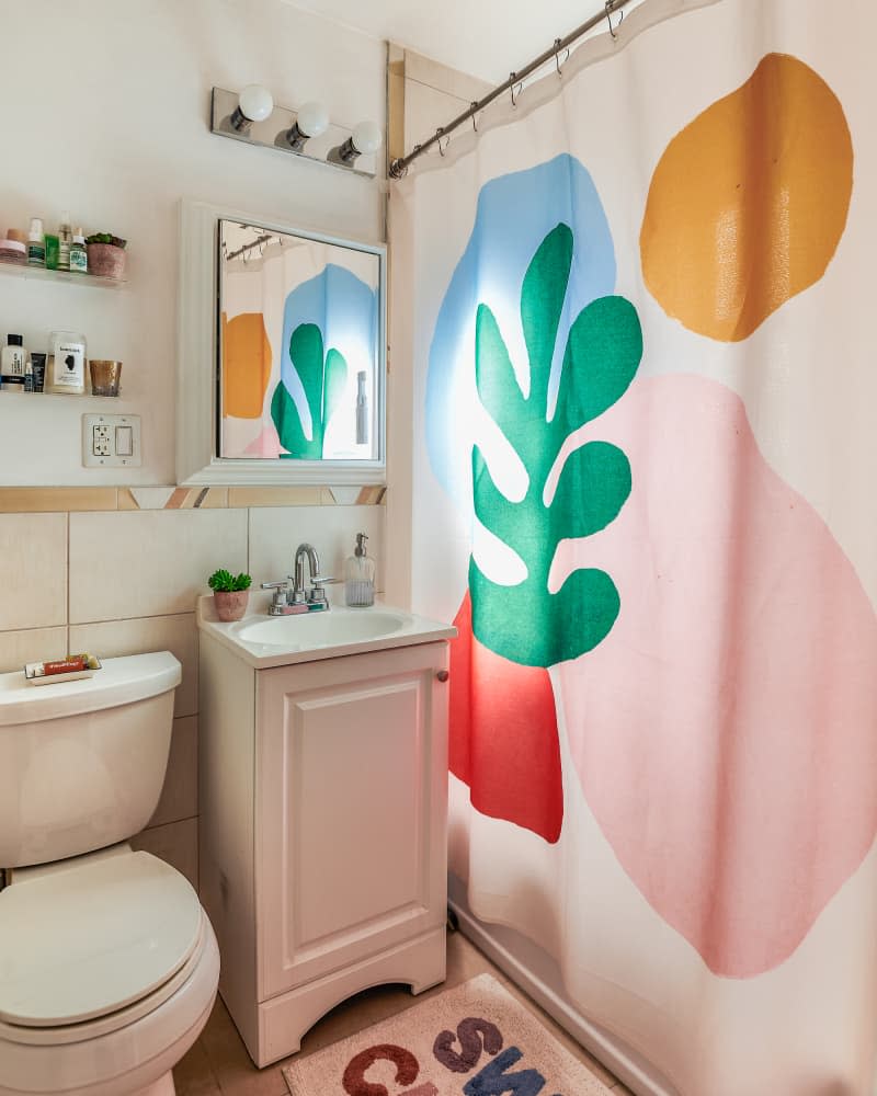 A cramped but colorful bathroom with wall shelves