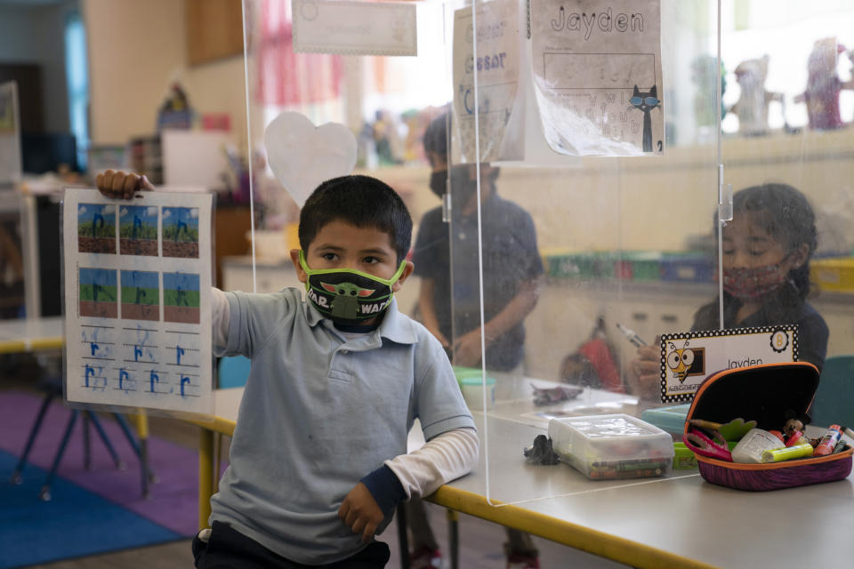 FILE - In this March 18, 2021, file photo, Cesar Verdugo, 5, shows his work to his teacher in a pre-kindergarten class at West Orange Elementary School in Orange, Calif. With a massive infusion of federal aid coming their way, schools across the U.S. are weighing how to use the windfall to ease the harm of the pandemic — and to tackle problems that existed long before the coronavirus. (AP Photo/Jae C. Hong, File)