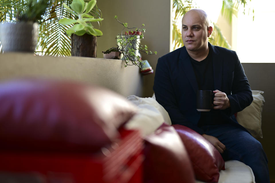 Omar Mediavilla, who urges his brother Jerick (Florida resident) to exercise the right to vote that the island's residents do not have, drinks a cup of coffee at his balcony in Toa Alta, Puerto Rico, Sunday, Oct. 18, 2020. President Donald Trump and former Vice President Joe Biden are targeting Puerto Rico in a way never seen before to gather the attention of tens of thousands of potential voters in the battleground state of Florida. (AP Photo/Carlos Giusti)