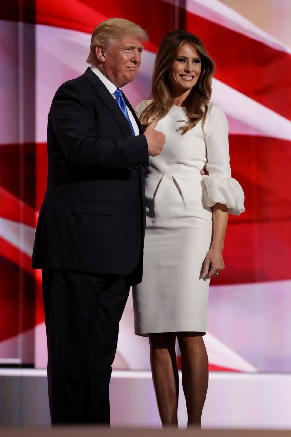 <p>Posing in front of a crowd, Melania stood with her husband in a fitted white dress with ruffled sleeves. <i>[Photo: Getty]</i> </p>