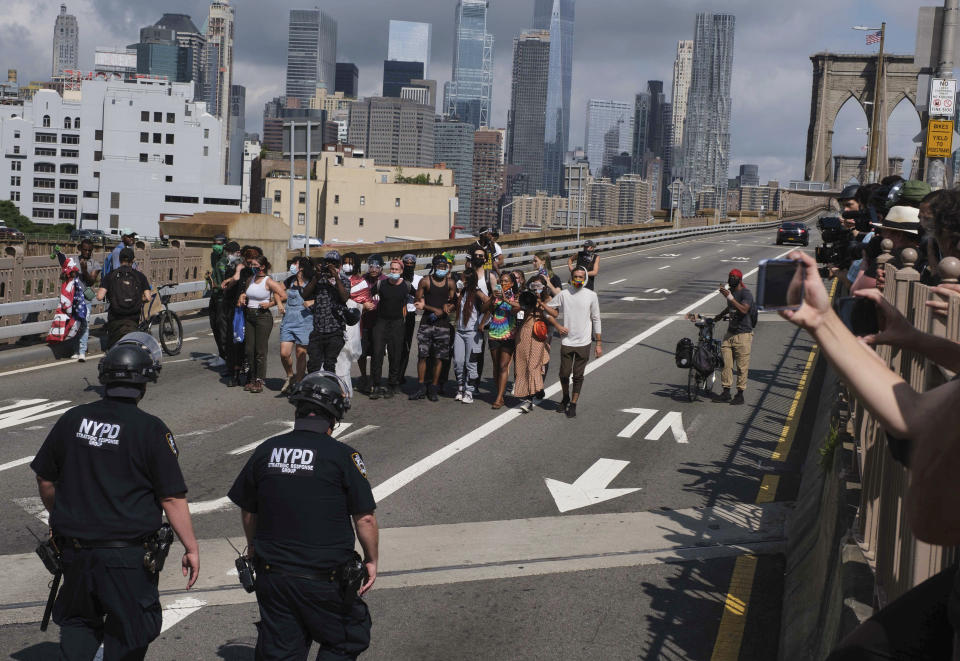 NYPD stand on the Brooklyn Bridge as Black Lives Matter protester Wednesday, July 15, 2020, in New York. Several New York City police officers were attacked and injured Wednesday on the Brooklyn Bridge during a protest sparked by the death of George Floyd. Police say at least four officers were hurt, including the department’s chief, and more than a dozen people were arrested. (AP Photo/Yuki Iwamura)