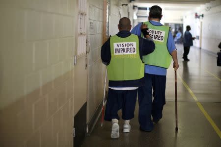 Inmates help each other walk down a corridor at the California Medical Facility prison in Vacaville, California, U.S., May 22, 2018. REUTERS/Lucy Nicholson