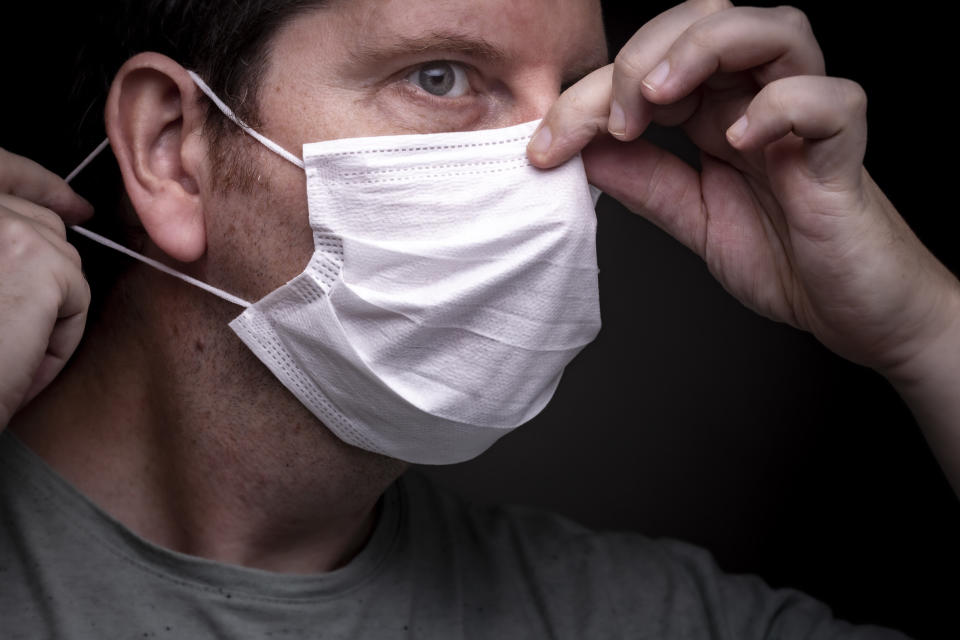 Man fits coronavirus face mask close to nose adjusts wire to stop hot air fogging on glasses