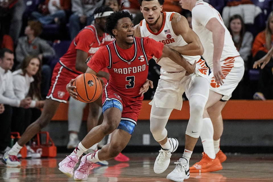 Radford guard Kenyon Giles (3) works against Clemson guard Chase Hunter (1) during the first half of an NCAA college basketball game, Friday, Dec. 29, 2023, in Clemson, S.C. (AP Photo/Mike Stewart)