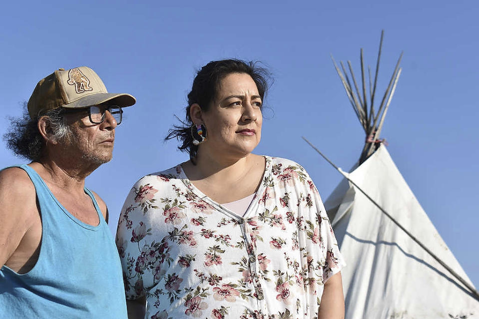 In this Thursday, May 20, 2021, photo, Fawn Wasin Zi, right, poses with her father, Terry Yellow Fat, in front of a tent on the Standing Rock Sioux Reservation in Fort Yates, North Dakota. The pipeline fight stirs bitter memories in Fawn Wasin Zi, a biology teacher who chairs the Standing Rock renewable energy power authority. (AP Photo/Matthew Brown)