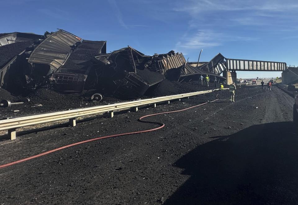 In this photo released by the Pueblo County Sheriff's Office, police respond to the scene of a train derailment near Pueblo, Colo., Sunday, Oct. 15, 2023. The train derailment Sunday spewed coal and mangled train cars across the highway. (Joshua Johnson/Pueblo County Sheriff's Office via AP)