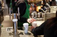 A barista serves beverages in single use cups inside a Starbucks in London