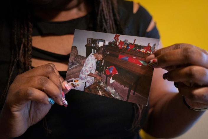 Tenai Leali, 47, of Detroit, shows a photograph of her grandmother Virginia McClendon opening presents on Christmas Eve, a family tradition that continued for many years, at her home in Detroit on Sept. 27, 2022. Leali inherited her grandparent's home but the property isn't in her name, and she worries about not being able to pass the home down to her children.