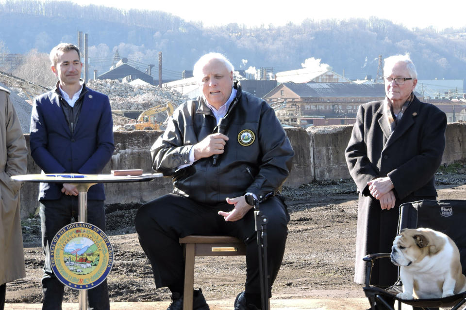 West Virginia Gov. Jim Justice, center, flanked by Form Energy CEO Mateo Jaramillo, left, and Weirton Mayor Harold Miller and Babydog at right, speaks about House Bill 2882, legislation which will provide $105 million toward Form Energy's planned battery manufacturing facility, Friday, Feb. 24, 2023, in Weirton, W.Va. (Craig Howell/The Weirton Daily Times via AP)