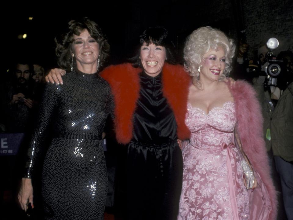 Jane, Lily, and Dolly smiling in gowns and walking on a red carpet.