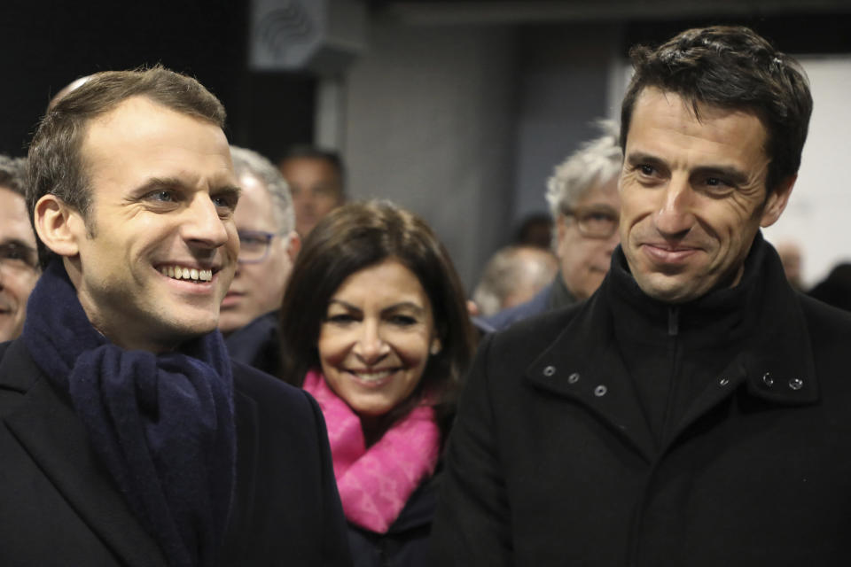 FILE - In this Feb. 27, 2018, file photo, France's President Emmanuel Macron, Paris mayor Anne Hidalgo, center, and Paris 2024 Games' chief Tony Estanguet, right, attend the inauguration of the Olympic Committee site for the Paris 2024 Olympic games and 2024 Paralympic games at the Stade de France stadium in Saint-Denis, outside Paris. The 2024 Paris Olympics emerges fully on Sunday, Aug. 8, 2021, from its unexpected extra year in the shadows with a formal handover from Tokyo. Macron and Estanguet began working together within days of the French presidential election in May 2017. (Ludovic Marin/Pool Photo via AP, File)