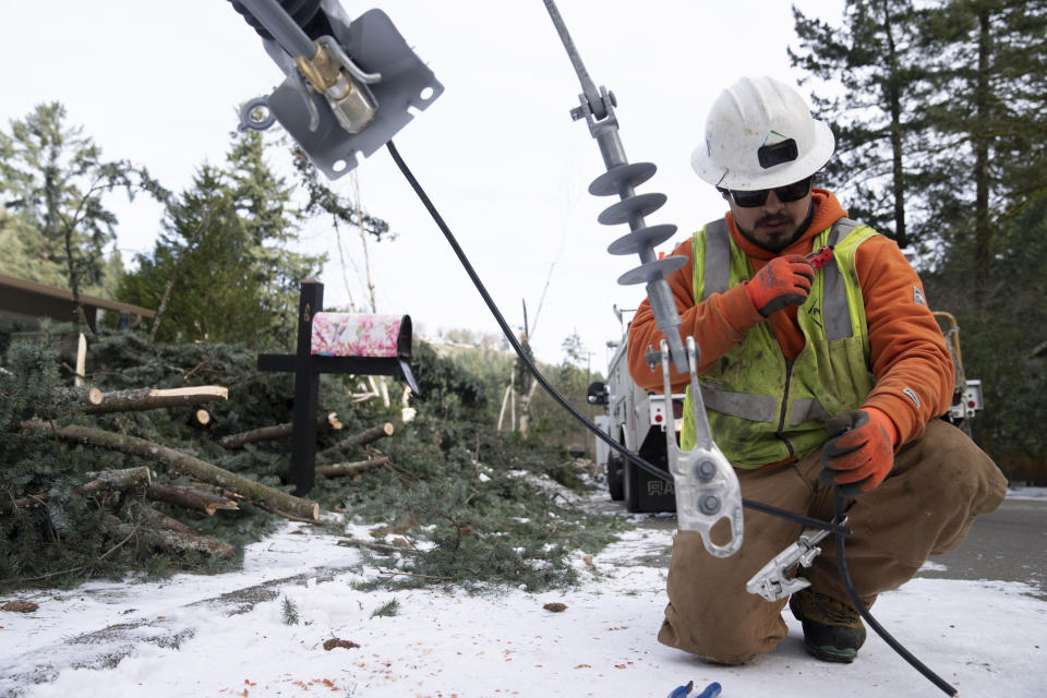 A worker from PG&E works to install a new power line as crews work on restoring power to the area after a storm on Tuesday, Jan. 16, 2024, in Lake Oswego, Ore. (AP Photo/Jenny Kane)