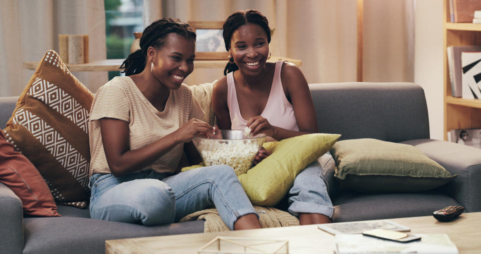 friends sharing a bowl of popcorn on the couch at home