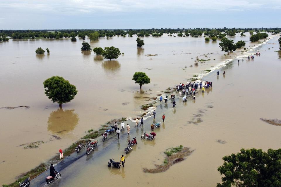 People walk through floodwaters after heavy rainfall in Hadeja, Nigeria, on Sept 19, 2022. (AP Photo)