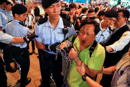 A pro-democracy activist, carrying chains used in protest, is taken away by policemen as protesters are arrested at a monument symbolising the city's handover from British to Chinese rule, a day before Chinese President Xi Jinping is due to arrive for the celebrations, in Hong Kong, China June 28, 2017. REUTERS/Damir Sagolj