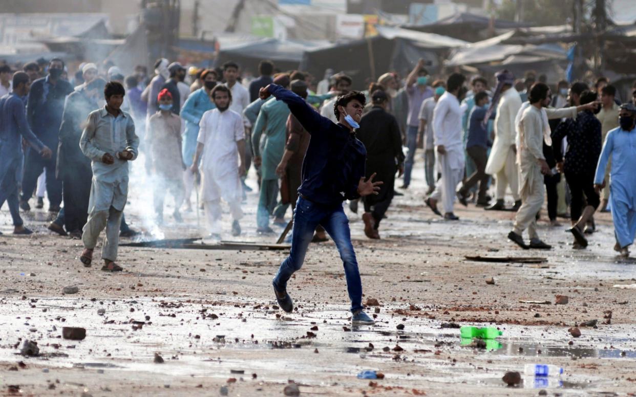A supporter of the Tehreek-e-Labaik Pakistan (TLP) Islamist political party hurls stones towards police (not pictured) during a protest against the arrest of their leader in Lahore, Pakistan April 13, 2021.
