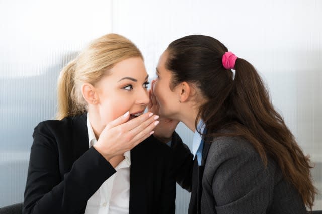 Businesswoman Whispering Into A Female Colleague Ear