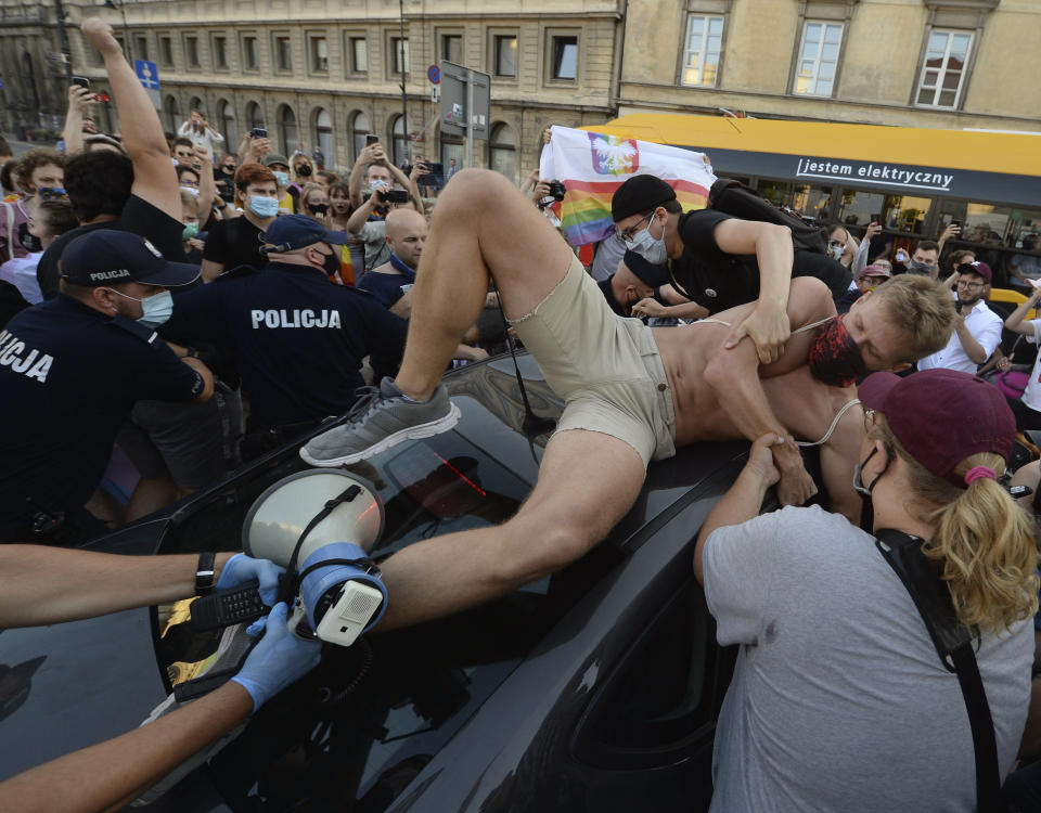 An activist climbs onto a police car to protest the detention of an LGBT activist in Warsaw, Poland, Friday, Aug. 7, 2020. The incident comes amid rising tensions in Poland between LGBT activists and a conservative government that is opposed to LGBT rights. (AP Photo/Czarek Sokolowski)