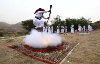 Mientras uno de los hombres está sobre la alfombra con el arma en la mano, el resto del grupo observa su hazaña.<br><br>Crédito: REUTERS/Mohamed Al Hwaity