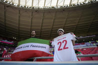 An Iran supporter, right, holds a shirt that reads 'Mahsa Amini 22' as another displays a flag that reads 'Woman Life Freedom' prior to the start of the World Cup group B soccer match between Wales and Iran, at the Ahmad Bin Ali Stadium in Al Rayyan, Qatar, Friday, Nov. 25, 2022. (AP Photo/Alessandra Tarantino)