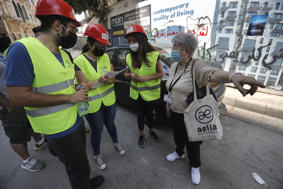 People who volunteered to help clean damaged homes and give other assistance, takes notes from a woman on a street that was damaged by last week's explosion, in Beirut, Lebanon, Tuesday, Aug. 11, 2020. In the absence of the state, acts of kindness and solidarity have been numerous and striking. Many extended a helping hand far beyond their circle of friends or family, taking to social media to spread the word that they have a room to host people free of charge. (AP Photo/Hussein Malla)