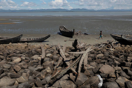 A child walks past remnants of some 20 boats that ferried Rohingya refugees fleeing violence in Myanmar, which were destroyed by Bangladeshi authorities the night before, at Shah Porir Dwip near Cox's Bazar, Bangladesh October 4, 2017. REUTERS/Damir Sagolj