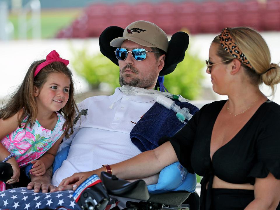 Lucy Frates, now 8, climbs onto the wheelchair of her dad, Pete, as her mom, Julie, looks on.