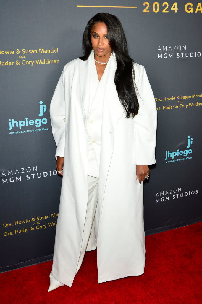 Ciara wears an elegant white suit with a long coat at an event