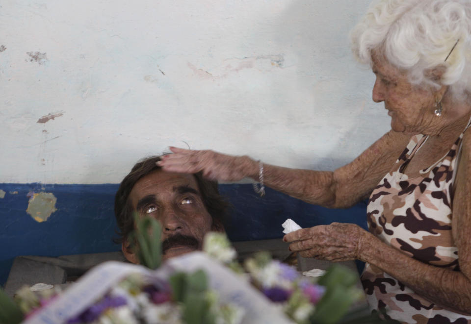 In this Feb. 5, 2014 photo, Divaldo Aguiar, who plays the part of Pachencho, in a mock funeral known as the Burial of Pachencho, lies inside a coffin as Carmen Zamora, who plays the part of his widow, puts her hand on his head, at a cemetery in Santiago de Las Vegas, Cuba. "Being reborn is the most beautiful thing there is in life," said Aguiar, who said he has played "Pachencho” for several years running. (AP Photo/Franklin Reyes)