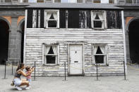 Alice Ridolfi, from Verona, helps her two years old son Leone take pictures of the house of U.S. civil rights campaigner Rosa Parks, rebuilt by artist Ryan Mendoza for public display, in Naples, Italy, Tuesday, Sept. 15, 2020. The rundown, paint-chipped Detroit house where Parks took refuge after her famous bus boycott is going on display in a setting that couldn't be more incongruous: the imposing central courtyard of the 18th century Royal Palace. (AP Photo/Gregorio Borgia)