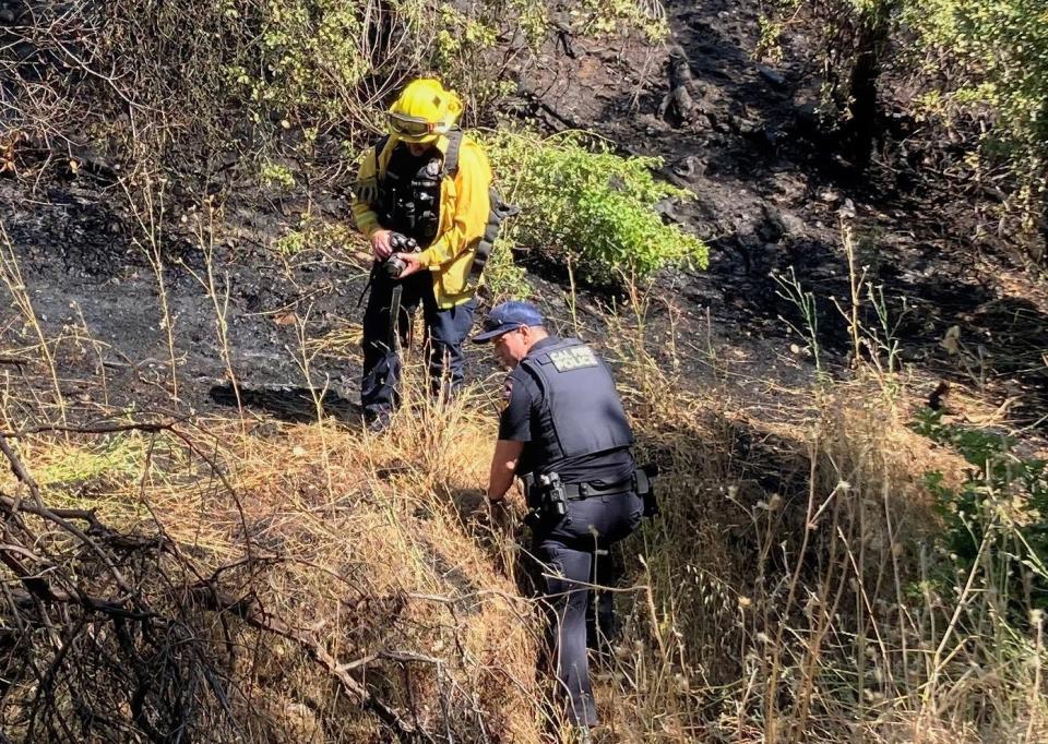 A Redding Fire Department investigator and Redding police officer investigate a fire off Barbara Road just north of Benton Drive in Redding on Friday morning, June 23, 2023.