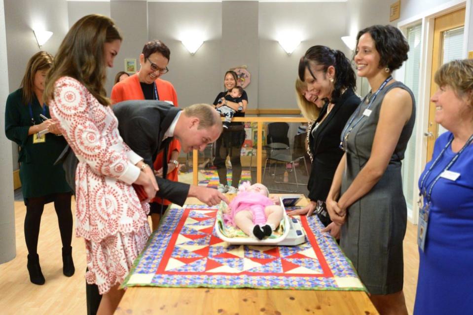 The Duke of Cambridge tickles a baby as his wife Kate, the Duchess of Cambridge looks on during a tour of Sheway, a centre that provides support for native women, in Vancouver, B.C., Sunday, Sept. 25, 2016. THE CANADIAN PRESS/Jonathan Hayward