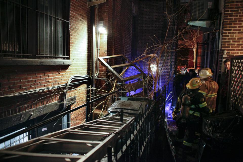 Firefighters gather in an alley Sunday, Jan. 12, 2014 after a fourth-floor balcony collapsed late Saturday at the historic John C. Bell building in the Rittenhouse Square section of Philadelphia, killing a young man and injuring two women, police said. Police say a 22-year-old man who suffered severe head and neck injuries in the fall was pronounced dead at a hospital early Sunday morning. The two women are in their 20s and suffered broken bones in their backs. They are listed in stable condition at two city hospitals. The man and two women, who were attending a birthday party, had stepped out onto the balcony to smoke cigarettes when the collapse occurred, authorities said. (AP Photo/ Joseph Kaczmarek)