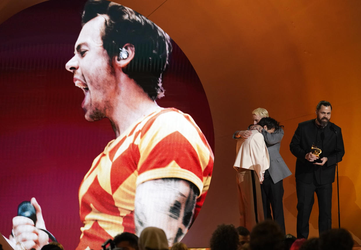 Harry Styles, left, embraces Kid Harpoon, center, while Tyler Johnson accepts the award for album of the year for "Harry's House" at the 65th annual Grammy Awards on Sunday, Feb. 5, 2023, in Los Angeles. (AP Photo/Chris Pizzello)