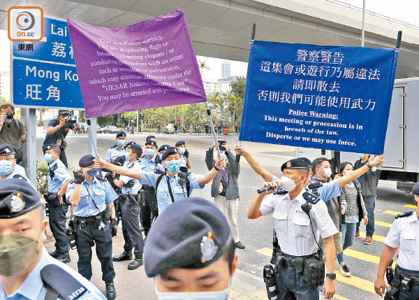 警員在法院外高舉港區國安法的紫色警告旗，同時舉起藍旗。（黃仲民攝）