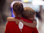 A tired boy is carried by his mother at the airport in Frankfurt, Germany, Saturday, Aug. 8, 2020. From Saturday on Covid-19 tests are mandatory for passengers coming from a high-risk-country. (AP Photo/Michael Probst)