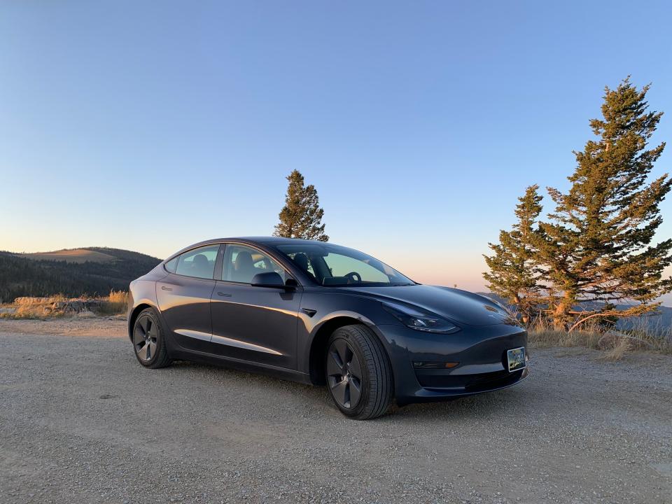 A dark grey Tesla parked at a campsite in Montana.