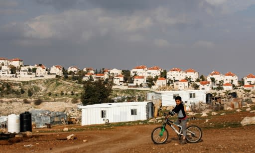 A boy rides a bicycle past Palestinian bedouin huts in the town of Eizariya in the occupied West Bank