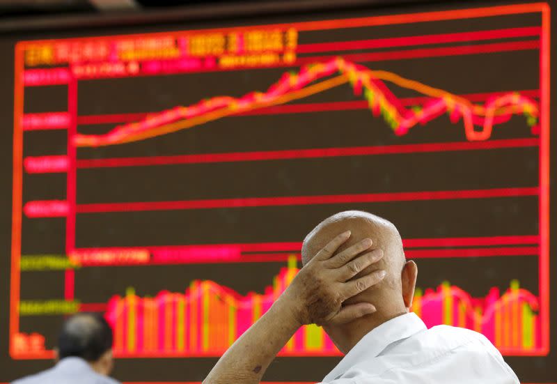 An investor looks at an electronic board showing stock information at a brokerage house in Beijing