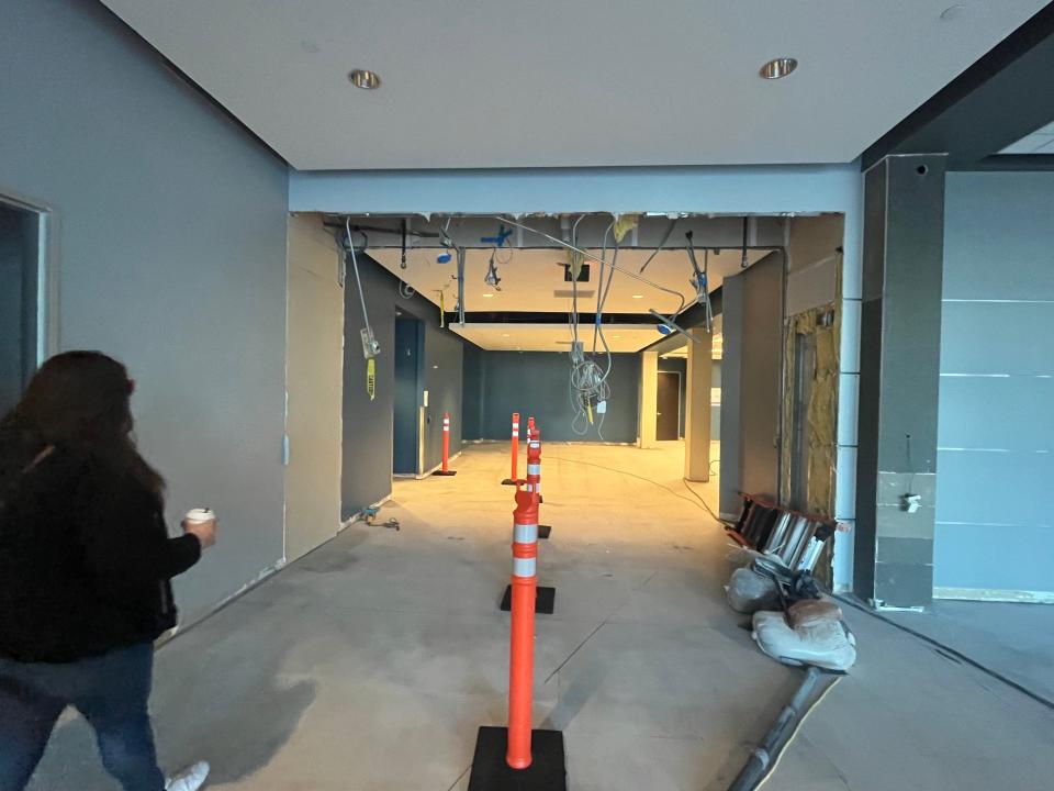 Photo inside an office partly under construction. Woman to the left walking inside.