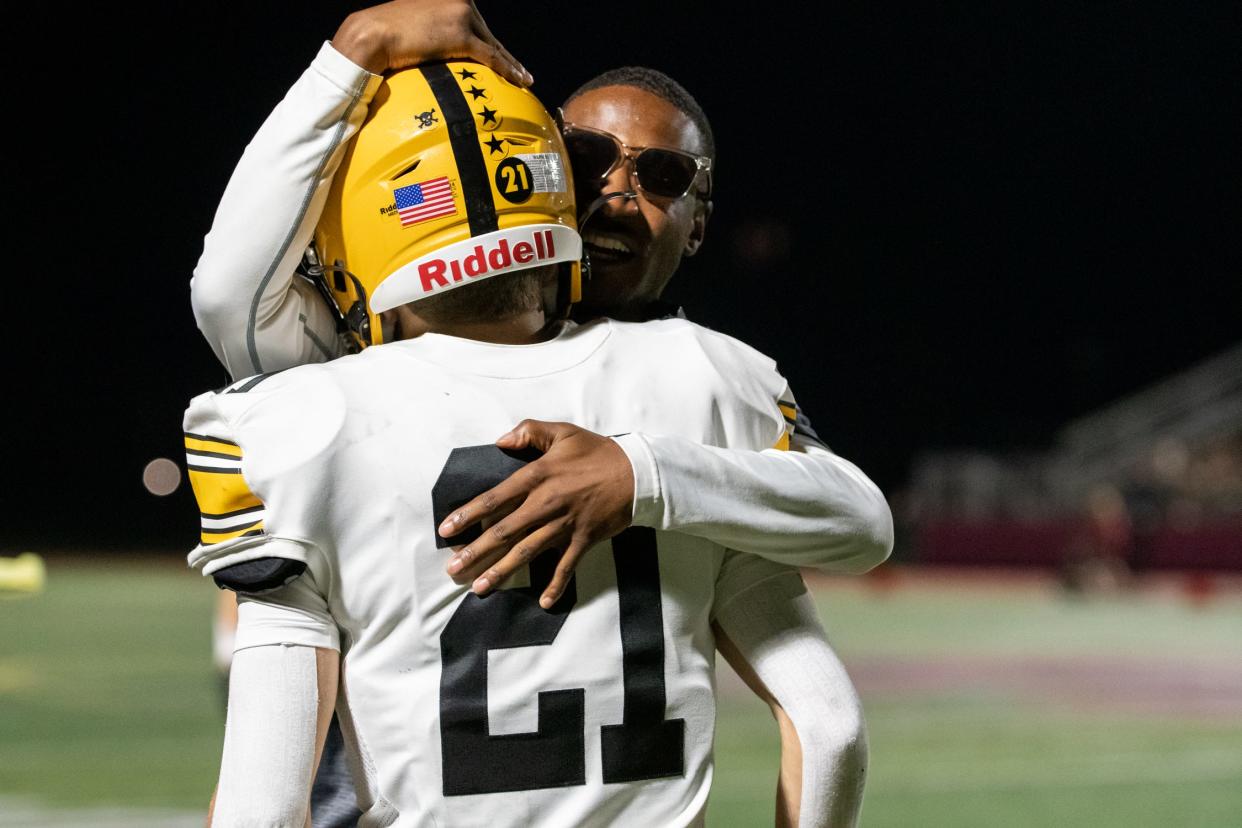 Central Bucks West assistant coach John Jones hugs cornerback Vance Morelli after Morelli's 51-yard interception return for a touchdown in a 35-14 win over Upper Dublin.