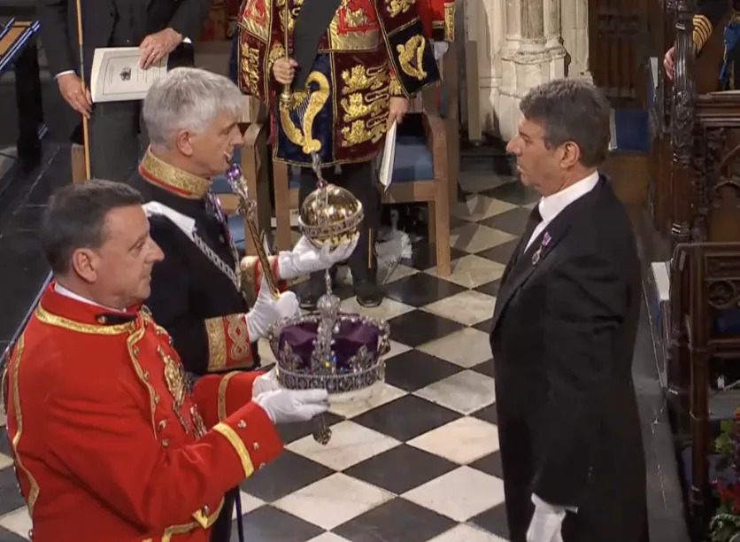 女王靈柩上的帝國王冠、君主權杖及寶球被取下，並由掌禮大臣折斷辦公杖置於靈柩上，象徵為君主服務的結束，隨後女王靈柩緩緩降入教堂地面。（圖取自直播）